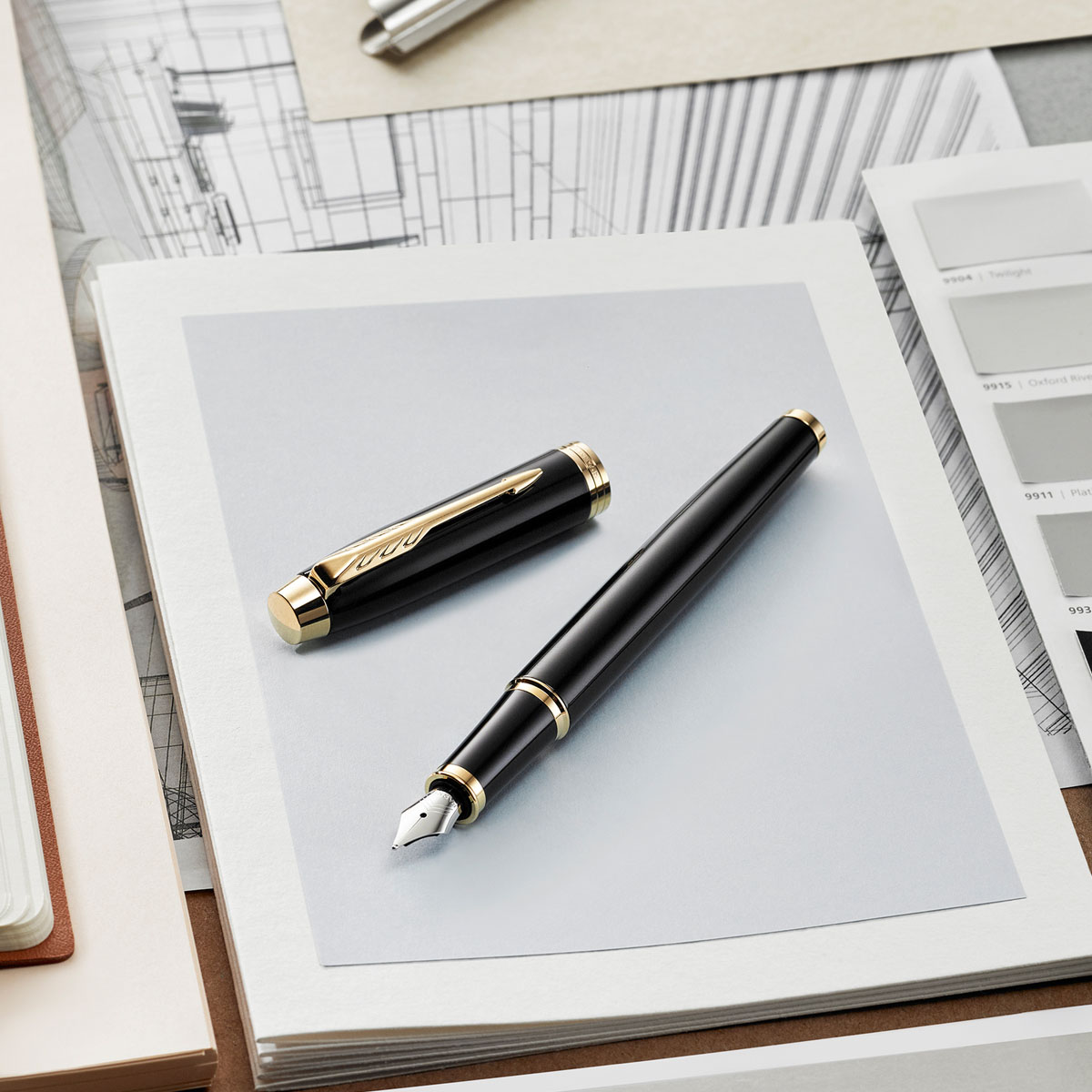 Pióro wieczne Parker IM Czarny GT [1931652] z otwartą skuwką, ułożone na kartkach papieru, z widocznymi złotymi wykończeniami.